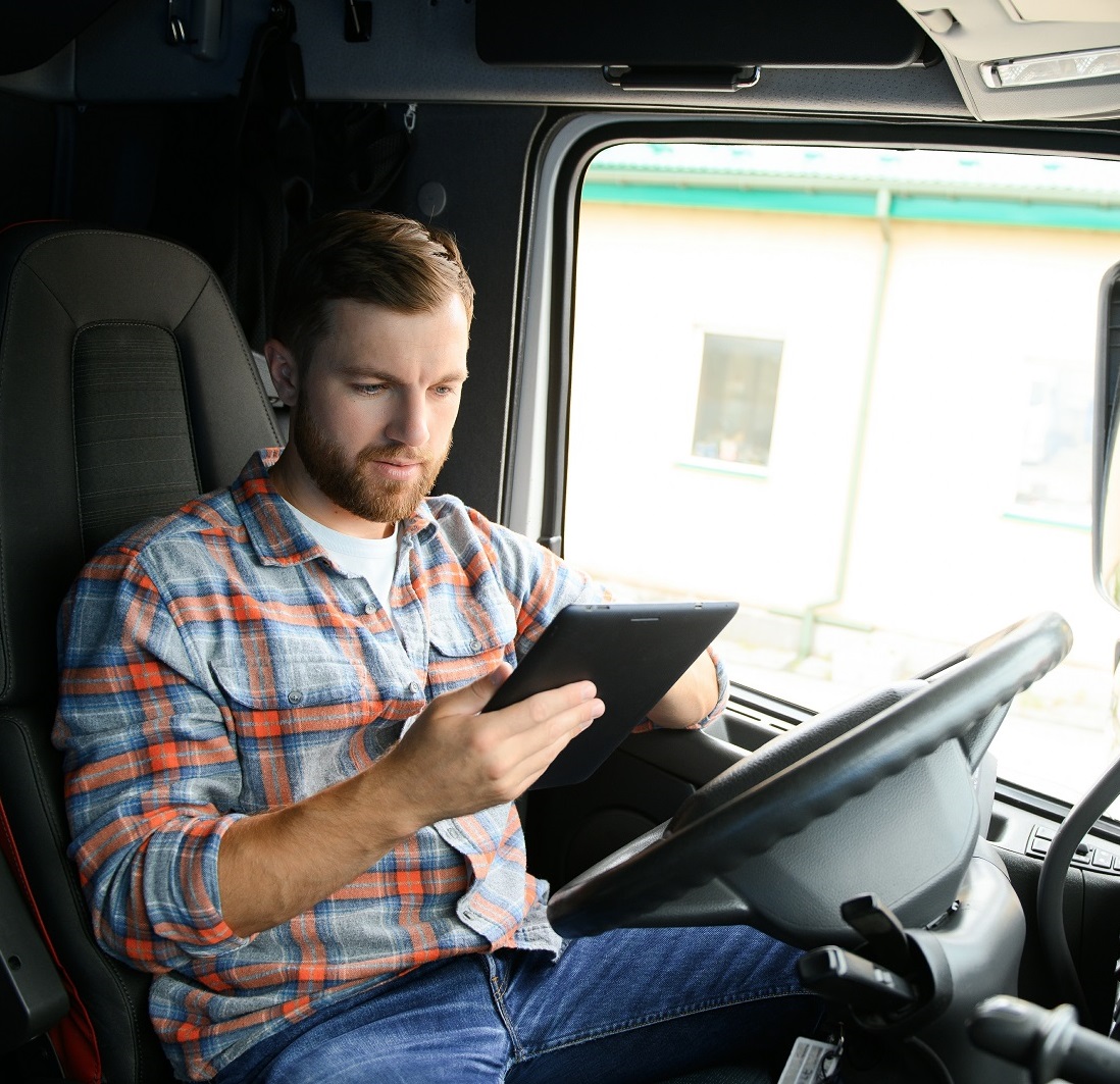 Man truck driver sitting behind wheel of car and holding digital tablet in his hands Man truck driver sitting behind wheel of car and holding digital tablet in his hands.