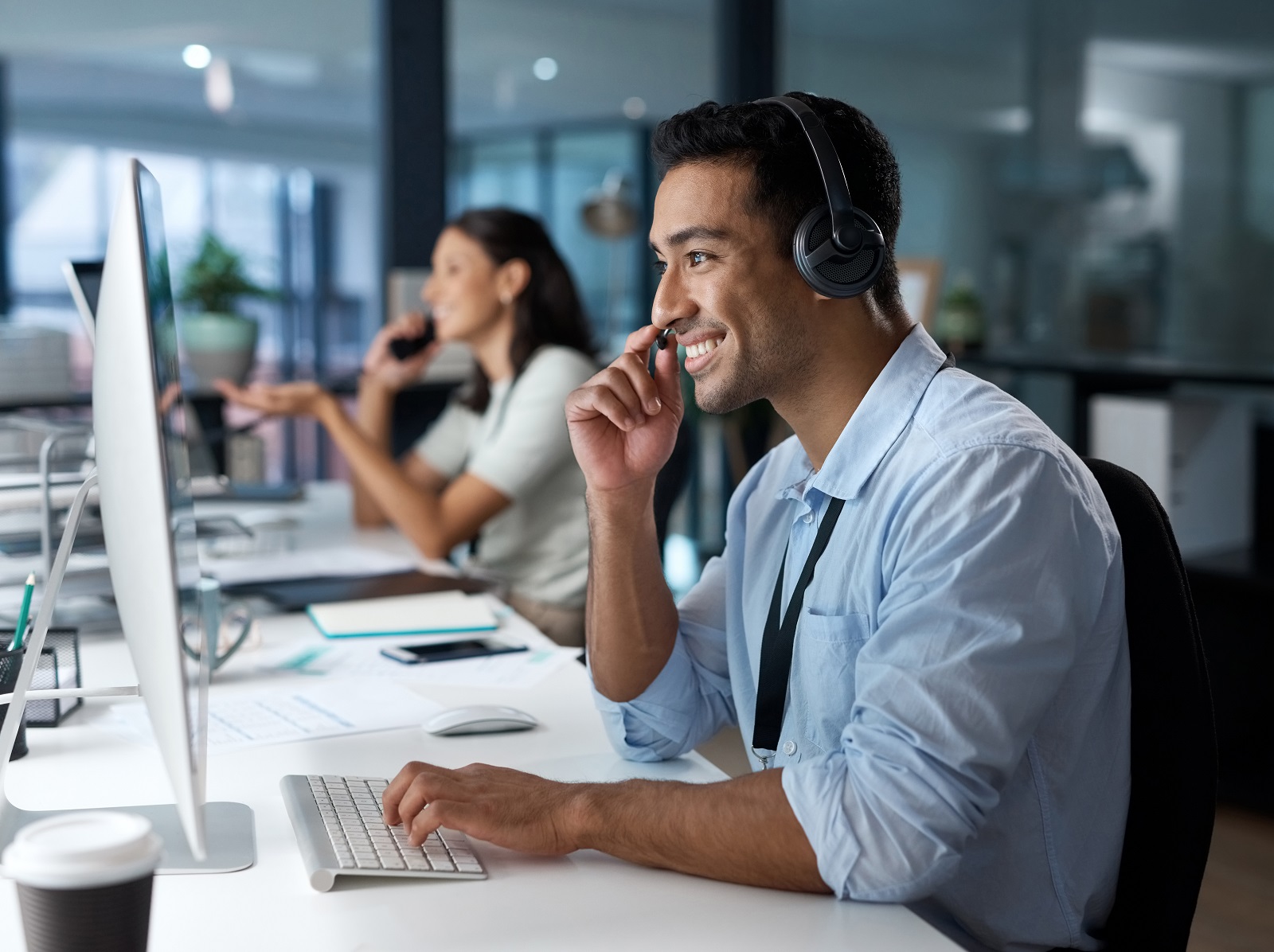 Shot of a young man using a headset and computer in a modern office. Shot of a young man using a headset and computer in a modern office.